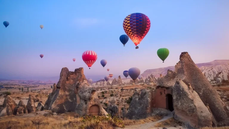 Hot air balloons floating over Cappadocia landscape at sunrise