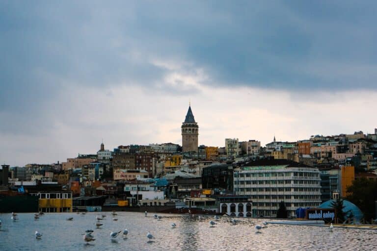 Panoramic view of the historical Galata Tower in Istanbul under a cloudy sky.