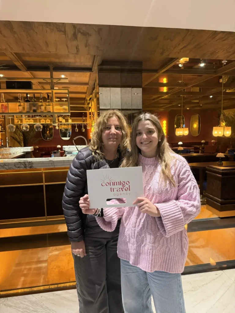 Happy guests with Conmigo Travel welcome sign at hotel lobby