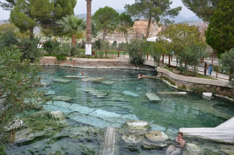 Cleopatra's Antique Pool at Pamukkale with turquoise thermal water surrounded by trees and ancient stone