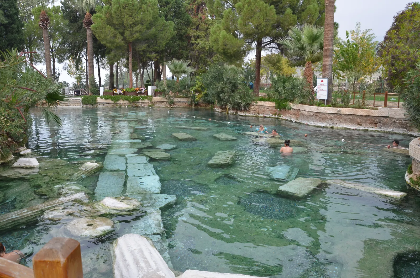 Visitors swimming among submerged Roman column drums in the warm thermal water of Cleopatra's Pool