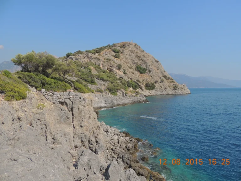 Gemiler Island seen from the mainland coast showing the rocky island with Byzantine church ruins above the turquoise sea