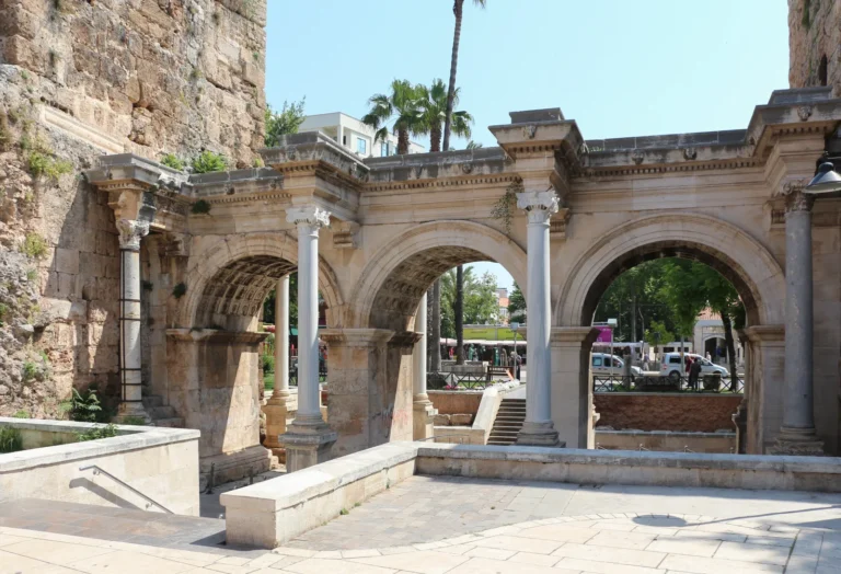 Hadrian's Gate triple marble arch in Antalya with Corinthian columns and the old town visible through the arches