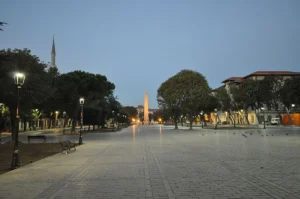 The Obelisk of Theodosius standing in Sultanahmet Square at dusk with a minaret in the background