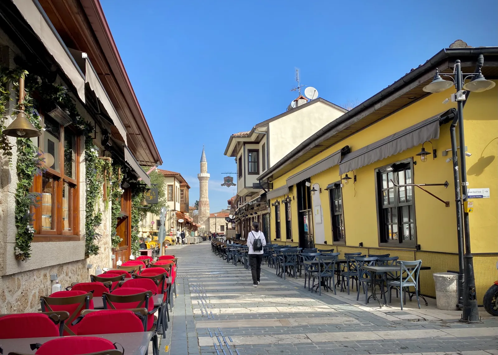 Narrow cobblestone street in Kaleici Antalya with Ottoman houses, bougainvillea, and a minaret visible in the background