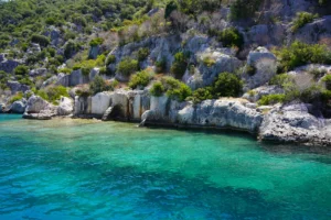 Submerged stone walls and ruins of Kekova sunken city visible through clear turquoise water from a boat