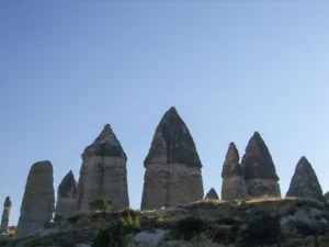 Tall columnar fairy chimneys in Love Valley Cappadocia with hikers walking the trail below