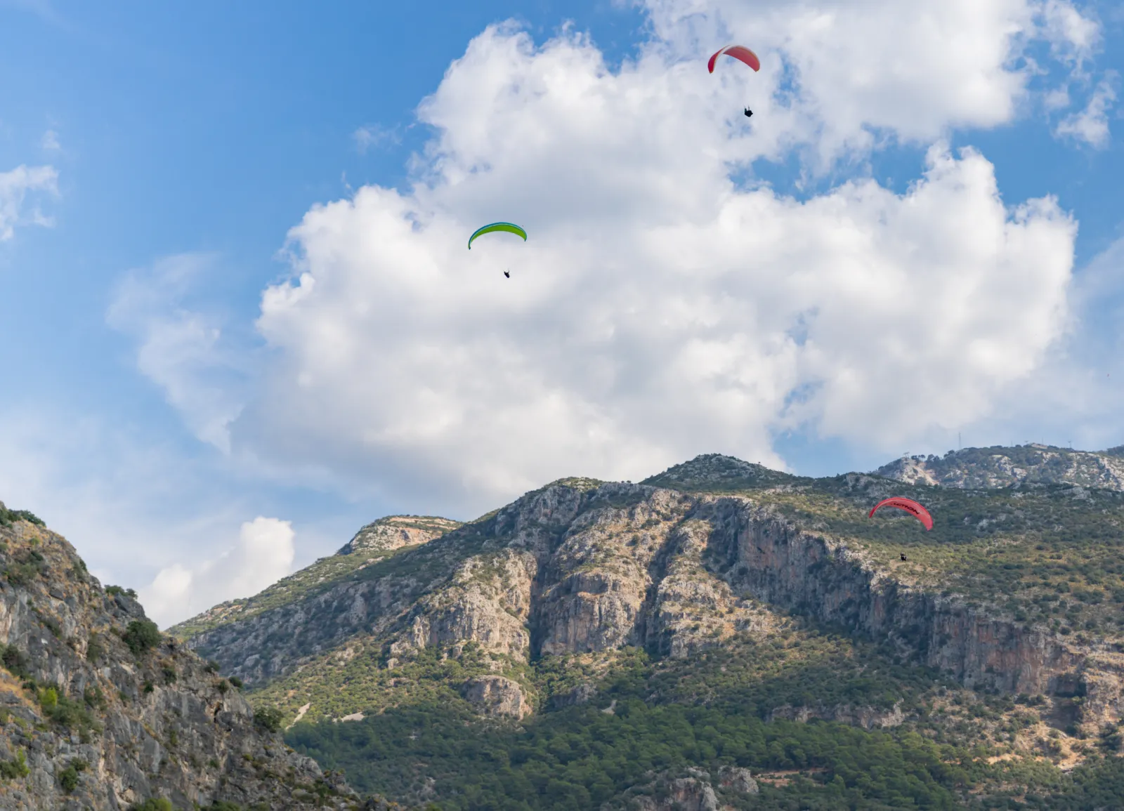 Tandem paraglider descending over Oludeniz Blue Lagoon with turquoise water and beach below