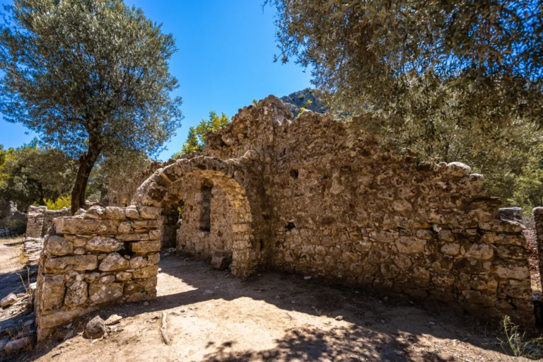The stone temple doorway of Olympos ancient city standing among trees in a forested river valley
