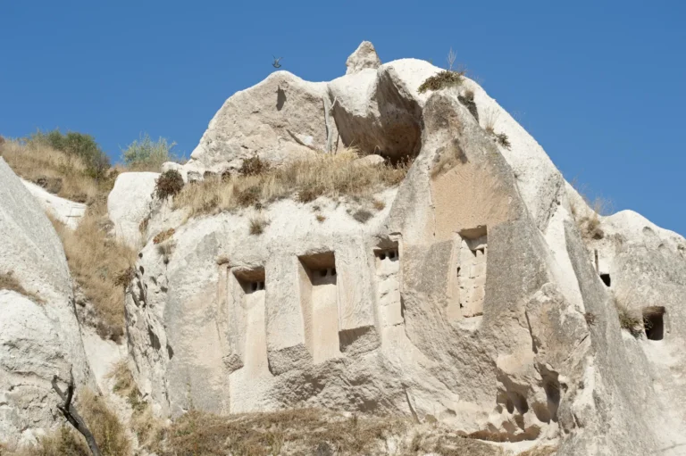 Carved dovecotes in the cliff faces of Pigeon Valley Cappadocia with the valley dropping away toward Goreme