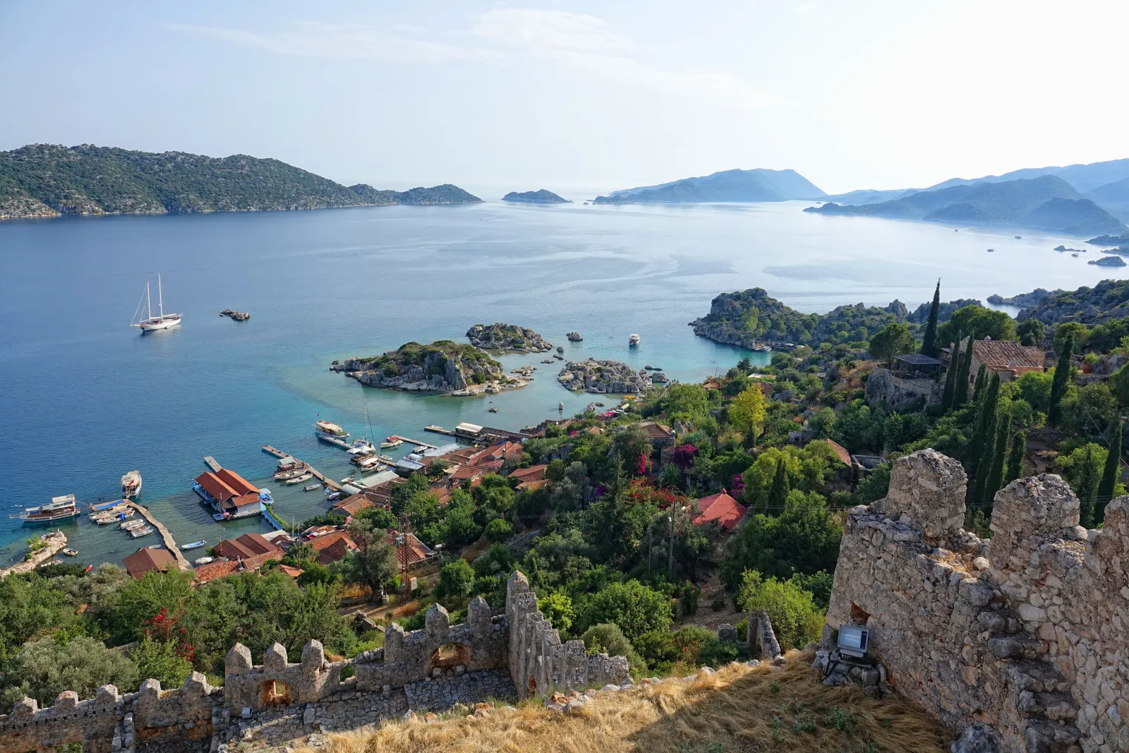 Simena Castle on the hilltop above Kalekoy village with stone houses descending to a small harbor and Lycian tombs