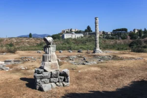 The single reconstructed column of the Temple of Artemis near Selcuk with a stork nest on top and the Basilica of St. John visible on the hill behind