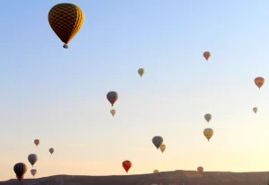 Hot air balloons rising at sunrise over the fairy chimney landscape of Cappadocia