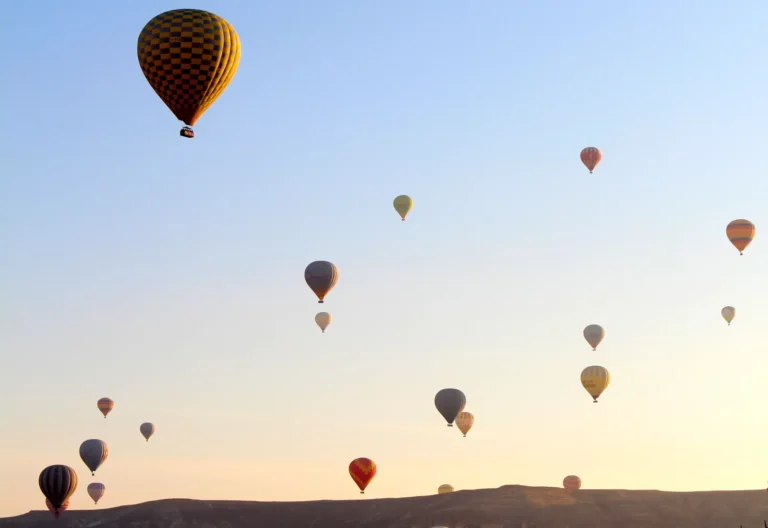 Hot air balloons rising at sunrise over the fairy chimney landscape of Cappadocia