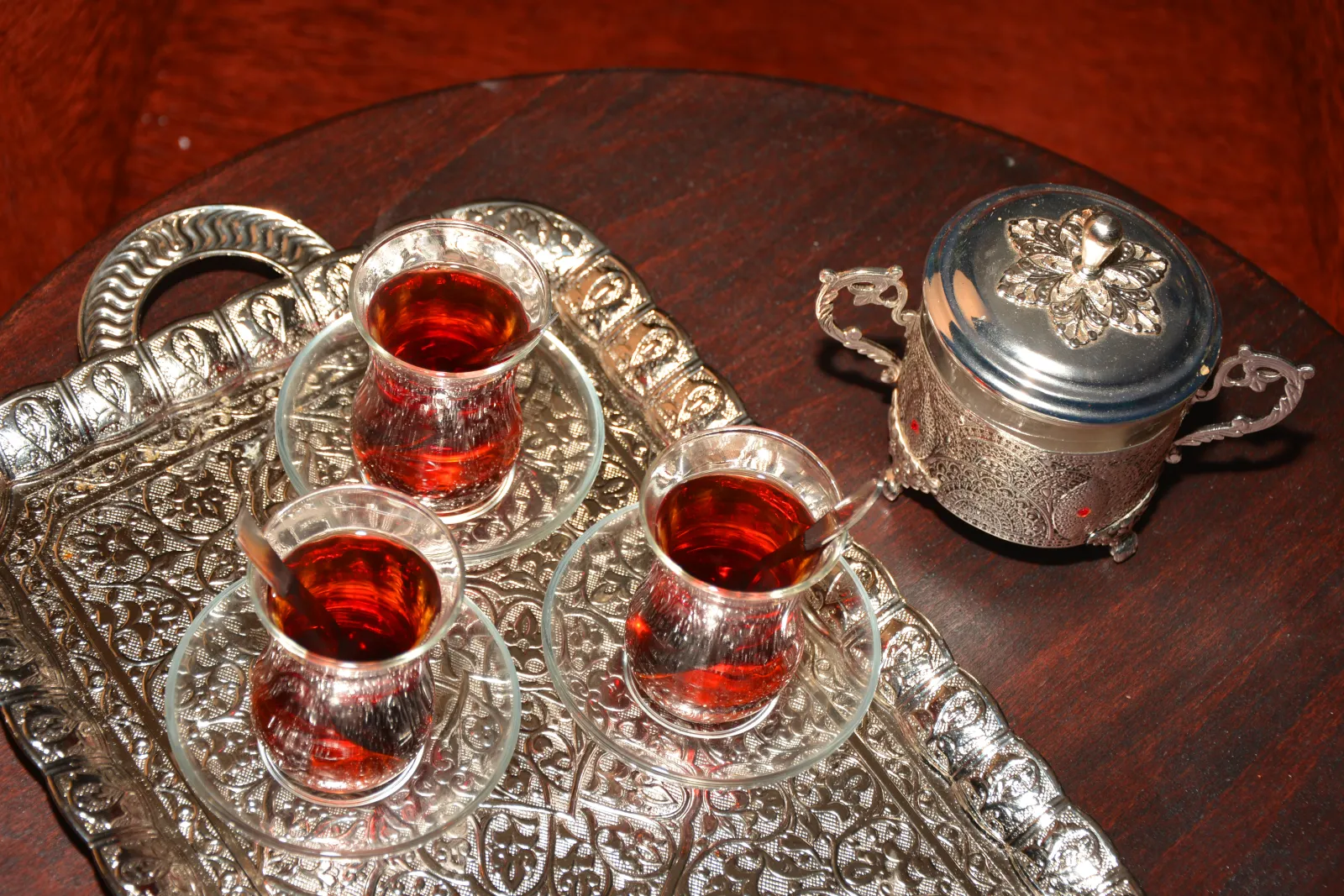 Turkish black tea in a tulip-shaped glass next to a tray of pistachio baklava